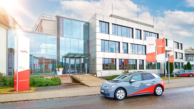 E-Auto vor Bürogebäude mit Glasfassade