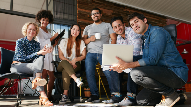 Full DEHN team standing front the camera, smiling, in an office with red walls