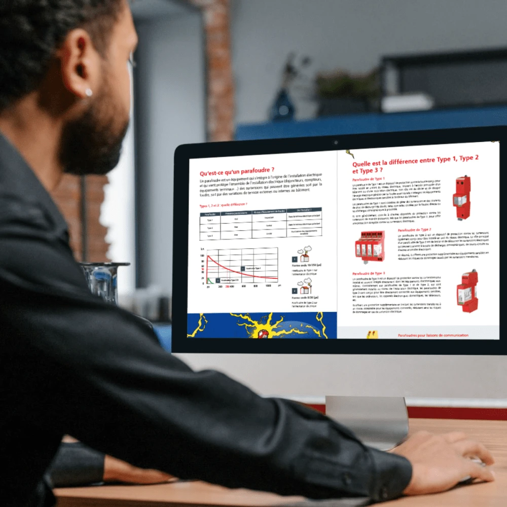 Man viewing guide about surge protection devices on computer screen showing Type 1, Type 2 and Type 3 explanations.