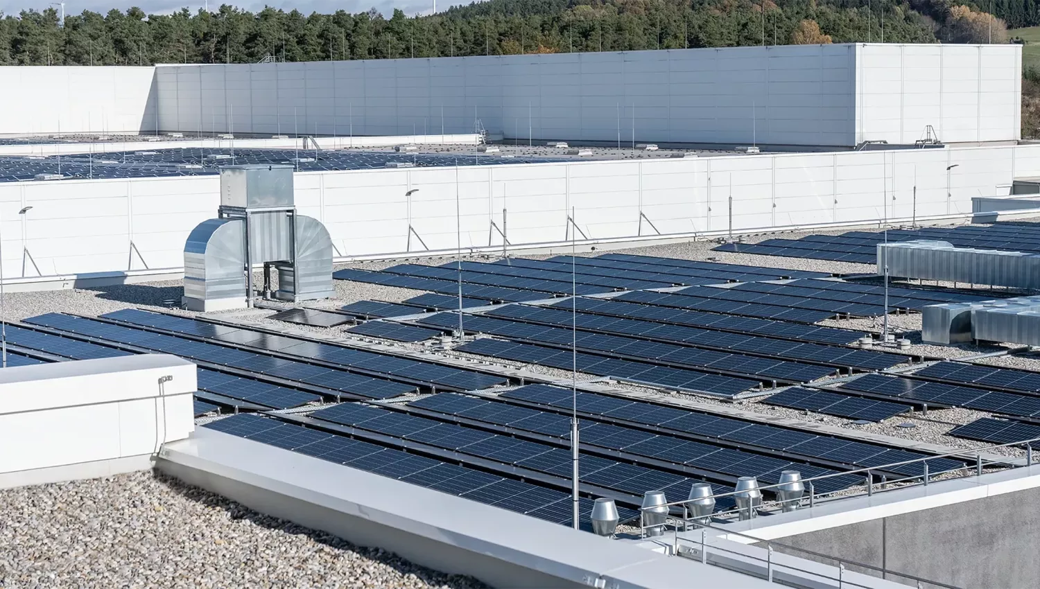 Flat roof with multiple rows of solar panels and ventilation units in the background.