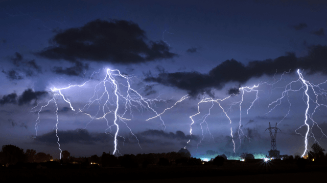 Storm with dark clouds in the night with several lightning strikes in the sky above a city