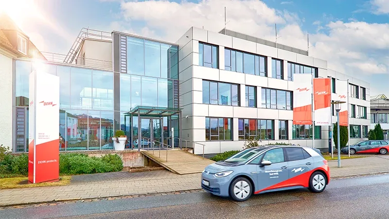 E-Auto vor Bürogebäude mit Glasfassade