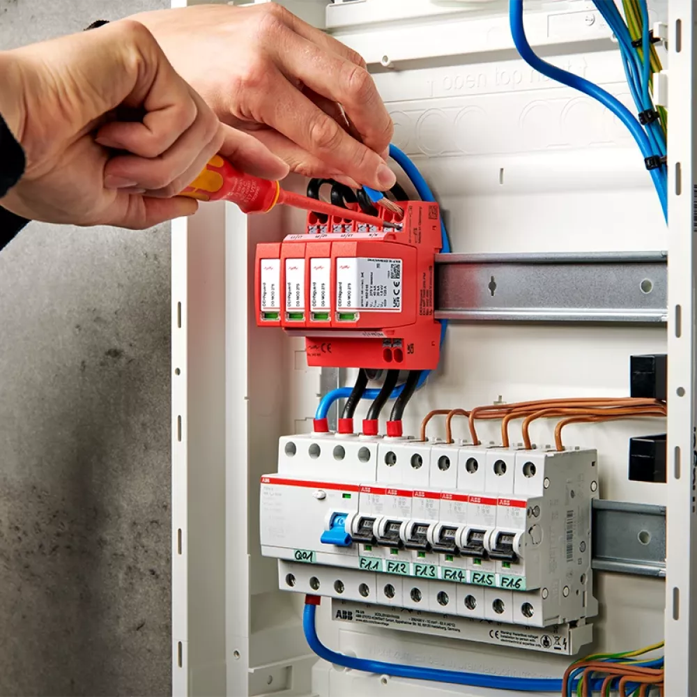 Electrician installs surge protection in a fuse box.