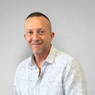 Portrait of a man with short hair, wearing a light patterned shirt.