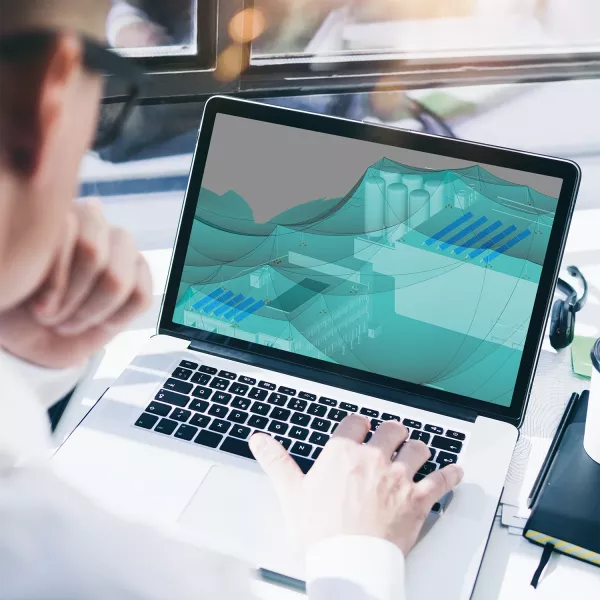 Laptop screen showing electrical planning software with a 3D protection zone model while a person works at the keyboard.