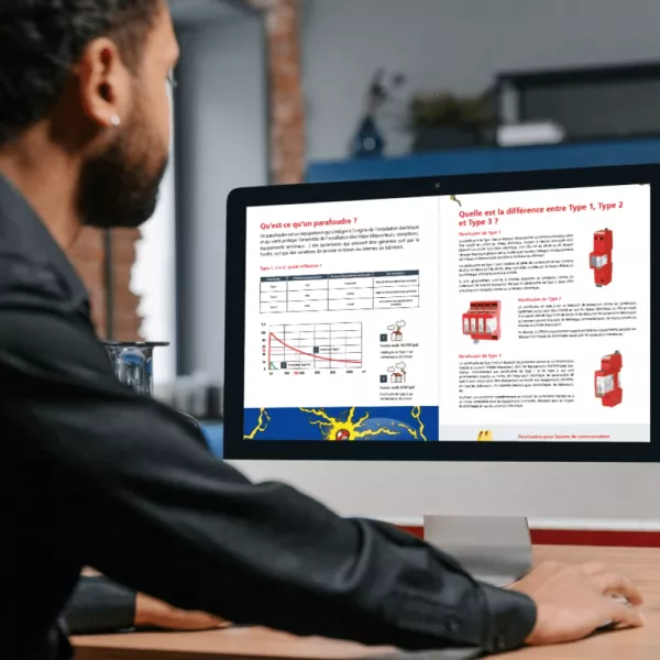 Man viewing guide about surge protection devices on computer screen showing Type 1, Type 2 and Type 3 explanations.