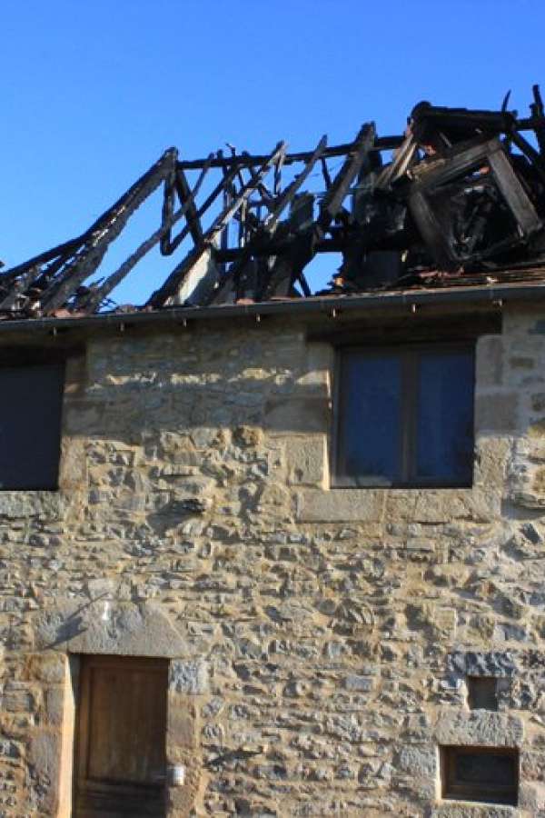 Photo de deux bâtiments anciens mitoyens aux pierres apparentes dont le toit s'est affaissé et a brûlé après un violent impact de foudre, image issue du journal la dépêche