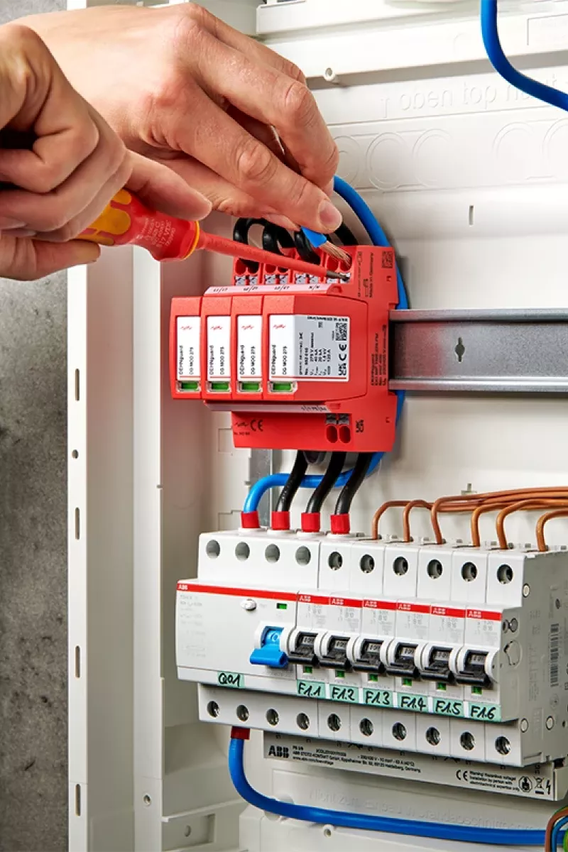 Electrician installs surge protection in a fuse box.